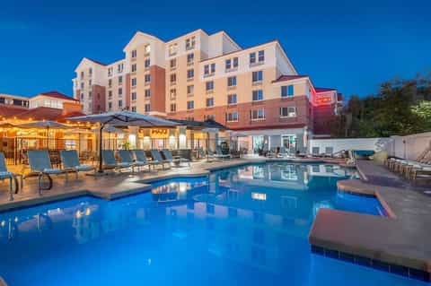 Hilton Garden Inn at dusk with illuminated pool, lounge chairs, and umbrellas