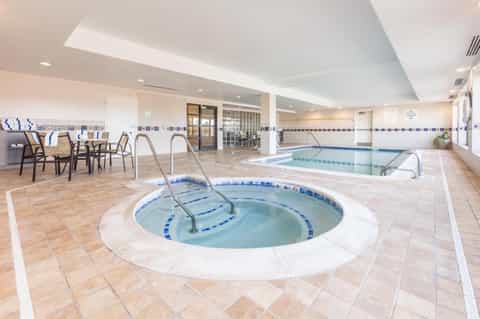 Indoor pool area with spa hot tub, lap pool, lounge seating, and casual dining space