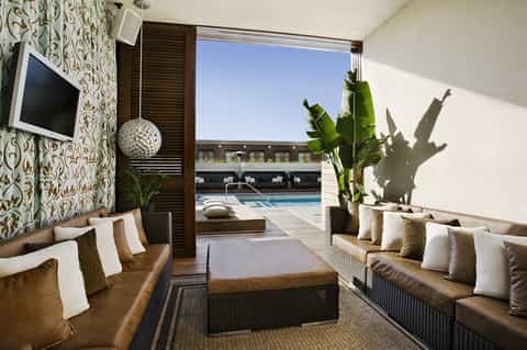 Luxurious lounge area with patterned wallpaper, tan seating, views to outdoor pool and ocean beyond