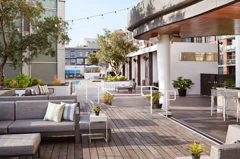 Rooftop terrace with gray lounge seating, striped pillows, wooden decking, and city views