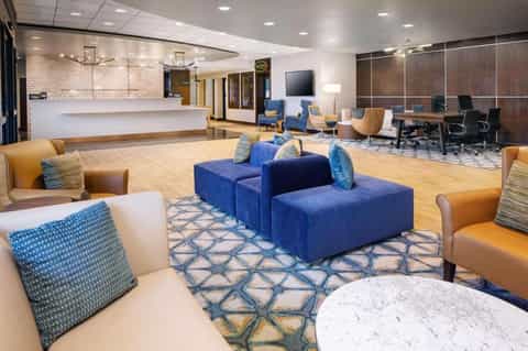 Modern hotel lobby lounge with blue and orange seating, marble flooring, and contemporary design