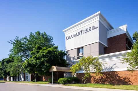 DoubleTree hotel exterior with brick and white trim, landscaped grounds, and clear blue sky
