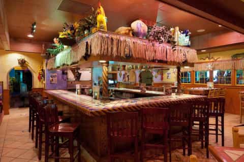 Tropical-themed restaurant interior with thatched roof bar, colorful décor, and wooden furnishings