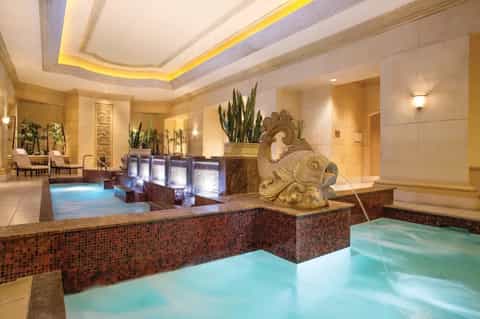 Luxurious indoor spa facility with multiple thermal pools, mosaic tile details, and ambient lighting
