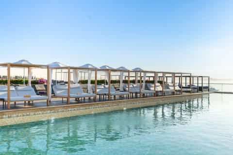 Resort poolside with wooden canopy loungers and turquoise water
