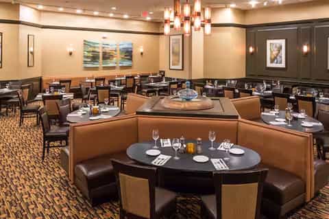 Upscale dining room with booth seating, round tables, and modern lighting fixtures