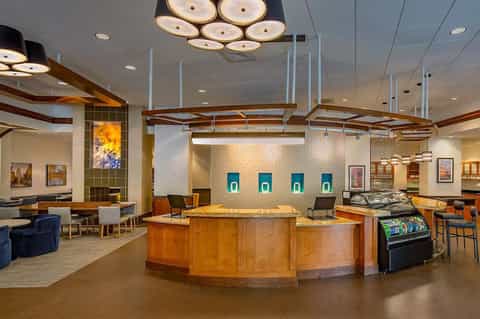 Hotel lobby with curved wooden reception desk, modern lighting, and seating areas