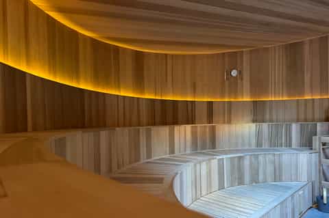 Modern sauna interior with curved wooden walls and ambient golden lighting