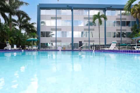 Bright blue rectangular swimming pool in front of modern multi-story hotel building