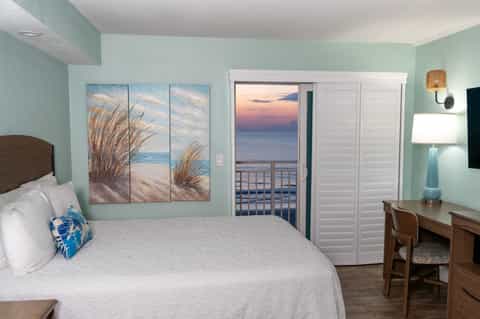 Beachfront hotel room with mint-green walls, ocean view balcony, and coastal decor
