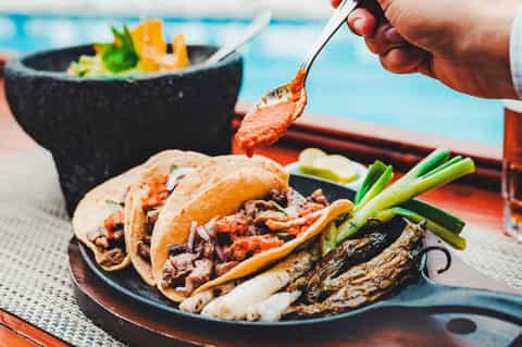 Plated tacos with grilled meat and vegetables served poolside with ocean view