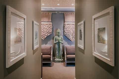 Spa meditation room with Buddha statue, decorative wall panels, and wooden benches