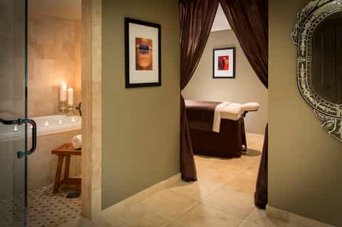 Spa bathroom with soaking tub, candles, and curtained relaxation area
