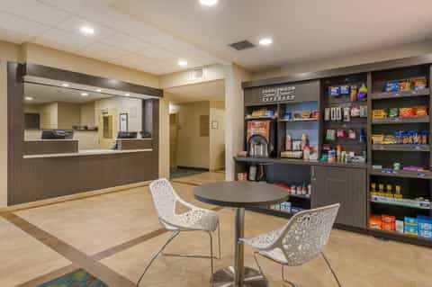 Hotel lobby with reception desk, seating area, and retail shelving display