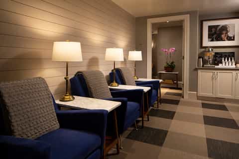 Spa waiting area with blue accent chairs, table lamps, wooden walls, and contemporary furnishings