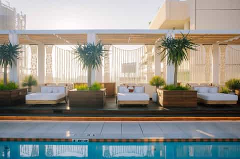 Luxury poolside lounge area with daybed seating and pergola shade structure