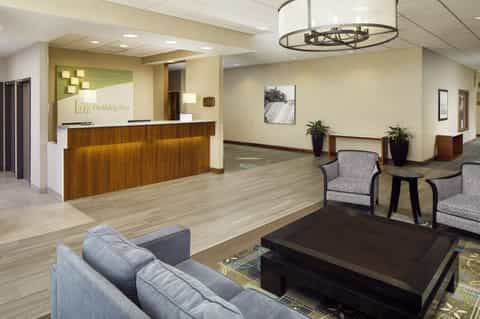 Bright hotel lobby with wooden reception desk, comfortable seating areas, and modern lighting