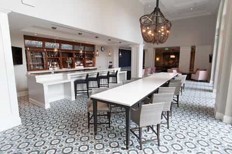 Upscale bar lounge with white countertops, dark seating, and ornate hanging light fixtures