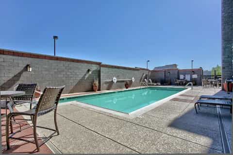 Outdoor swimming pool with lounge chairs and concrete deck overlooking brick building