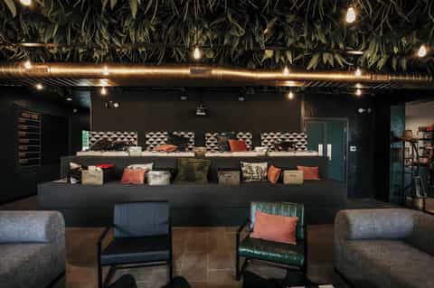 Modern hotel reception desk with black walls, geometric patterns, decorative pillows, and contemporary seating