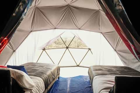 Interior view of glamping geodesic dome tent with two beds and geometric skylight