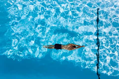 Overhead view of swimmer doing butterfly stroke in clear pool water
