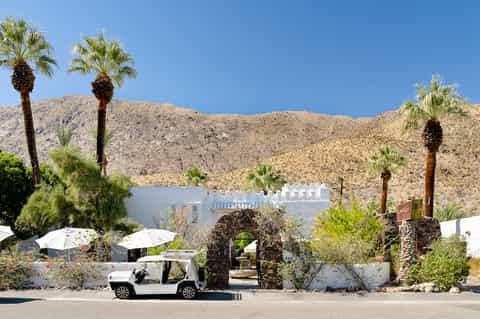 Desert resort entrance with white architecture, palm trees, and mountain backdrop
