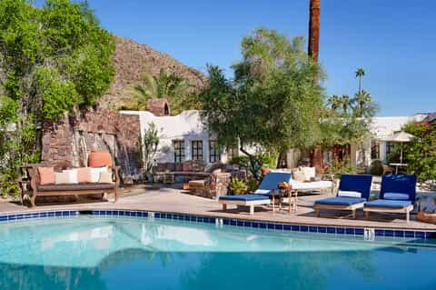 Resort pool area with lounge chairs, white umbrellas, and desert mountain landscape backdrop