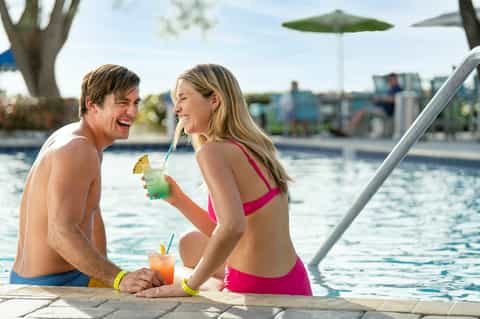 Couple enjoying tropical drinks by resort pool