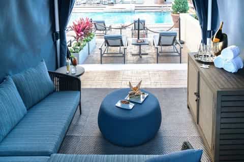 Covered poolside lounge area with blue seating, cocktails, and ocean view access