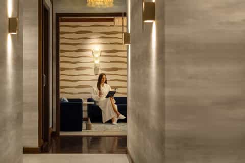 Contemporary hotel hallway with textured wall panels and woman sitting in lounge area