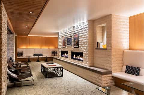 Modern spa lounge with fireplaces, comfortable seating, stone accents, and warm ambient lighting