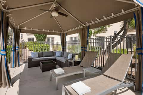 Covered patio lounge area with gray sectional sofa and lounge chairs under pergola