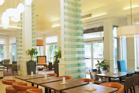 Bright hotel lobby with green tile columns, orange accents, and modern furnishings