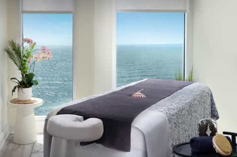 Oceanview spa massage table with sea vista through floor-to-ceiling windows