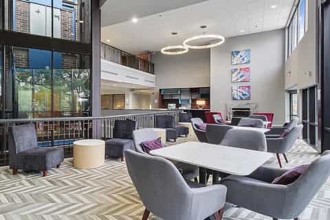 Contemporary resort lobby with seating area, fireplace, modern lighting, and mezzanine level