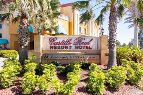 Casillo Real Resort Hotel sign with palm trees and landscaping under clear blue sky