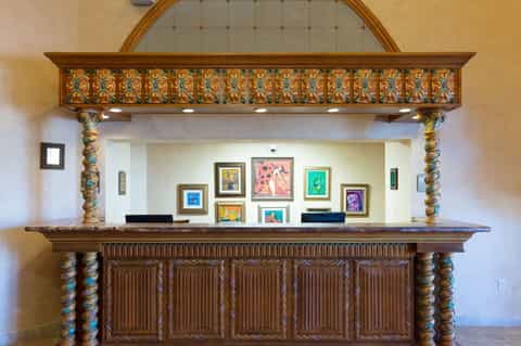 Ornate wooden hotel reception desk with decorative carved columns and colorful framed artwork