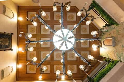 Ornate ceiling chandelier with decorative coffers and artistic lighting