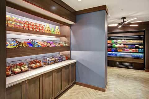Hotel convenience store with wooden shelving displaying snacks, beverages, and packaged goods