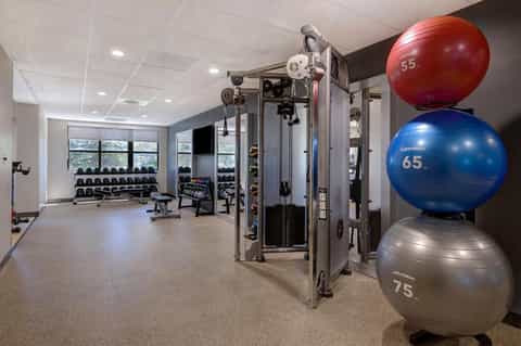 Fitness center with exercise equipment, dumbbells, medicine balls, and cable machines on carpeted floor
