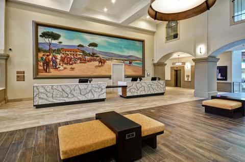 Spacious hotel lobby with dual reception desks, high ceilings, and large landscape artwork