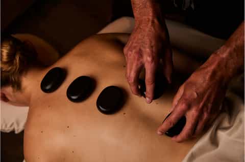 Hot stone massage therapy treatment being performed on client's back