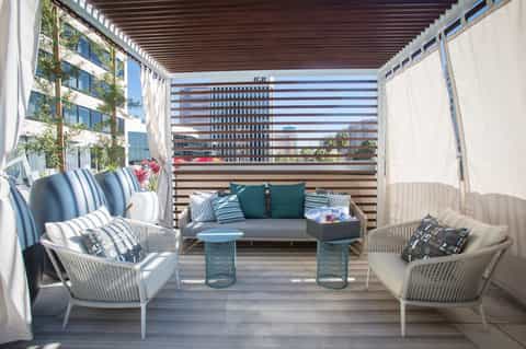 Covered balcony with wicker seating, striped wall backdrop, and city skyline views