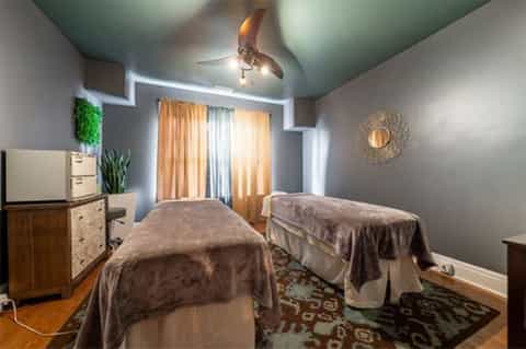 Spa treatment room with two massage tables and teal ceiling fan