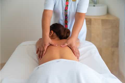 Therapist performing back massage on client at spa treatment table