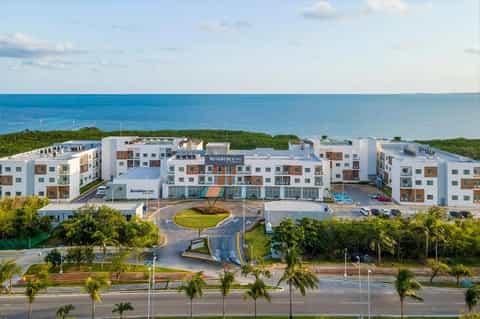 Oceanfront resort complex with white buildings overlooking turquoise water and palm trees