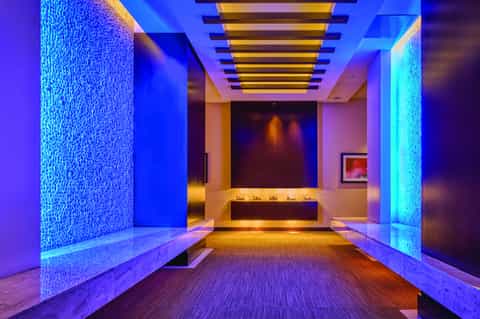 Modern spa corridor with blue and purple ambient lighting and water wall features
