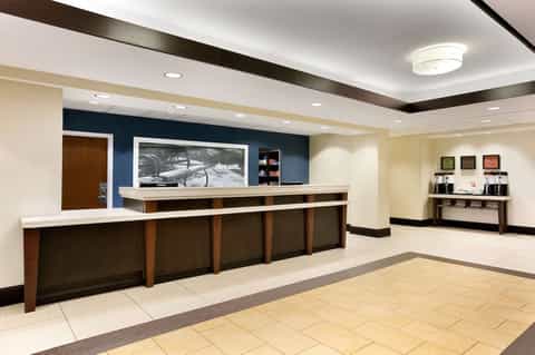 Modern hotel lobby with dark wood reception desk, blue accent wall, and polished tile flooring