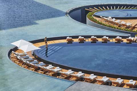 Curved infinity pool with lounge chairs and ocean views at a luxury resort